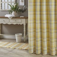 a yellow and white checkered shower curtain next to a table with a potted plant on it