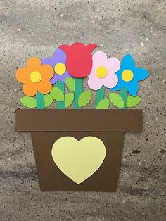 a cardboard flower pot with paper flowers in it and a heart cut out on the side