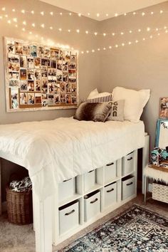 a white bed with lots of drawers underneath it and lights strung above the headboard