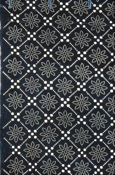 an old black and white rug with small dots on it's edges, in the shape of flowers