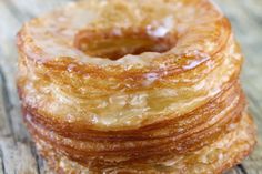 a stack of glazed donuts sitting on top of a wooden table