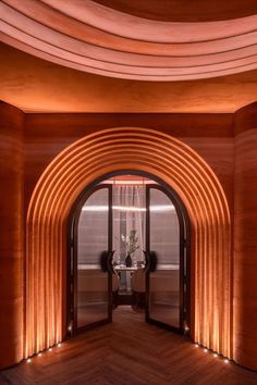 an arched doorway leads into a room with wooden walls and flooring that is lit by lights