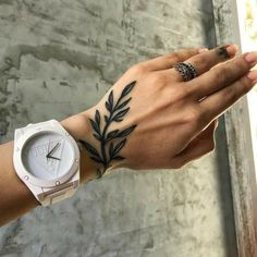 a woman's hand with a tattoo on it and a watch in the other hand