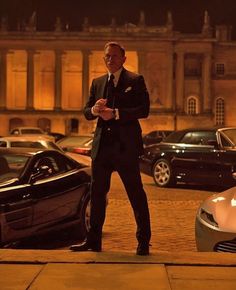 a man in a suit standing next to some cars