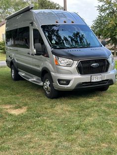 a silver van parked on top of a lush green field