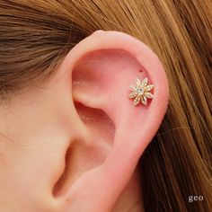 a woman's ear is adorned with a tiny flower and diamond studded in gold