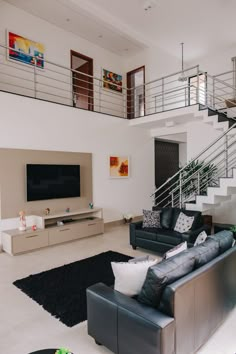 a living room with black leather couches and white walls