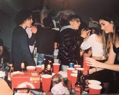 a group of people standing around a table filled with cups and drinks at a party