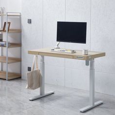 a computer desk with a monitor and keyboard on it in front of a white wall