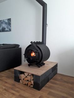 a wood burning stove sitting on top of a wooden platform in a living room next to a couch