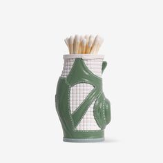 a green and white vase with toothbrushes in it