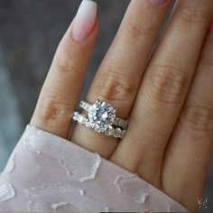 a close up of a person's hand with a diamond ring on their finger