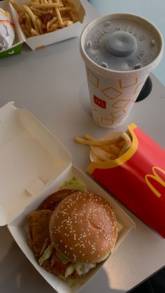 a hamburger and french fries are on a table next to a soda in a cup