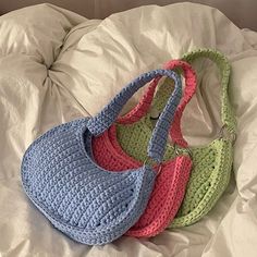 three crocheted purses sitting on top of a white bed covered in sheets