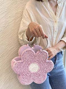 a woman holding a pink flower shaped purse