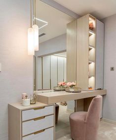 a dressing table and chair in a room with a large mirror on the wall above it