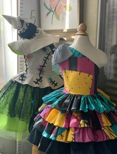 two mannequins dressed in brightly colored dresses, each with different designs on them