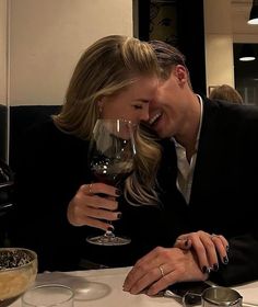 a man and woman sitting at a table with wine glasses