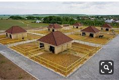 an aerial view of several buildings in the middle of a field with fencing around them