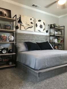 a bedroom with a bed, shelves and soccer balls on the wall above it's headboard