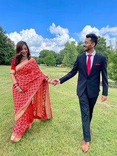 a man and woman holding hands while walking in the grass