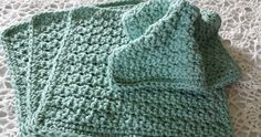 two green crocheted dishcloths sitting on top of a white doily