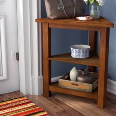 a wooden table with a purse and flowers on it in front of a blue wall