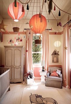 a baby's room decorated in pink and white with lanterns hanging from the ceiling