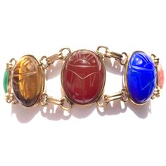 Looking for colorful jewelry? A go with everything good luck bracelet? This vintage scarab bracelet has seven gorgeous semi precious stones, set in 12K gold filled open bezels with double links in between. Gemstone scarabs are are a very nice size. This eye catching gold filled bracelet stands out all on its own! Era: Mid Century. Bracelet is 7.25 inches long by 0.8 inches wide. Scarabs with their settings are 21.5mm by 16.5mm.  Marks: Hallmark, 1/20 12K G. F., hallmark. Gemstones from spring ri Heirloom Multicolor Oval Jewelry, Multicolor Cabochon Costume Jewelry, Gold Oval Bohemian Bracelets, Oval Multicolor Jeweled Jewelry, Bohemian Gold Oval Bracelets, Vintage Multicolor Cabochon Jewelry, Antique Multi-stone Bracelets As Gift, Antique Multi-stone Bracelet As Gift, Vintage Multicolor Oval Jewelry