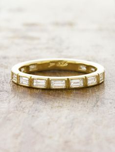 a yellow gold wedding band with baguettes set in the middle on a wooden surface