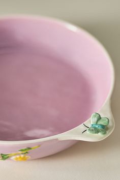 a close up of a pink bowl on a white surface with a green flower in the center