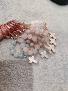 a woman's hand holding several bracelets with crosses on them