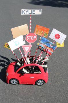 a red car with lots of stickers on it's hood parked in front of a street sign