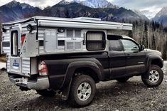 a truck with a camper attached to the back parked in front of some mountains