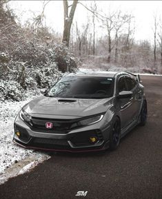 a gray car parked on the side of a road in front of snow covered trees