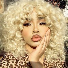 a woman with white hair and leopard print shirt holding her hands to her face while posing for the camera