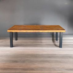 a wooden table sitting on top of a hard wood floor next to a gray wall