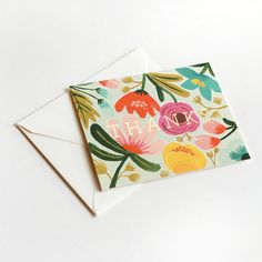 a thank card with colorful flowers and leaves on it, next to a white envelope