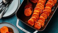 sausages are being cooked in a pan with sauce on the side and silverware next to it