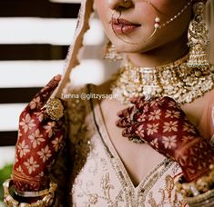 a woman in a bridal outfit with her hands on her face and nose piercings