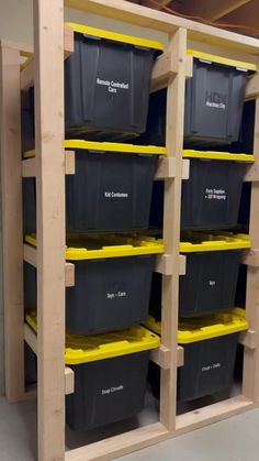 several bins are lined up on shelves in a storage area with yellow and black bins