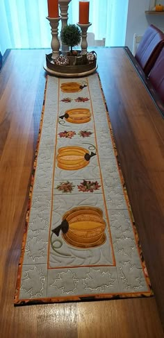 a table runner with candles on top of it and an orange candle in the center