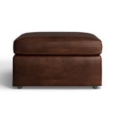 a brown leather ottoman sitting on top of a white floor