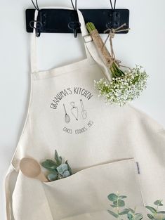 a kitchen apron hanging on a wall next to a potted plant and utensils