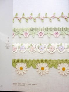 crocheted flowers and leaves are on the side of a piece of white fabric