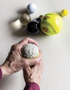 an older woman holding a ball in front of several other balls on a table top