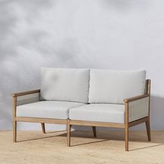 a white couch sitting on top of a hard wood floor next to a gray wall