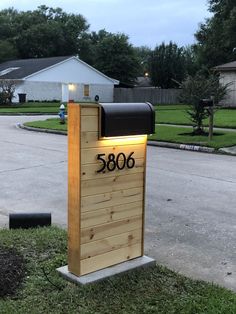 a wooden mailbox sitting on the side of a road next to a grass covered field