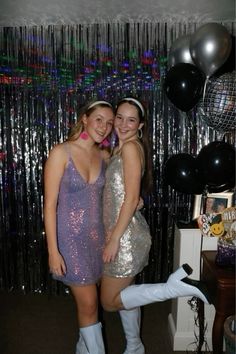 two young women standing next to each other in front of balloons