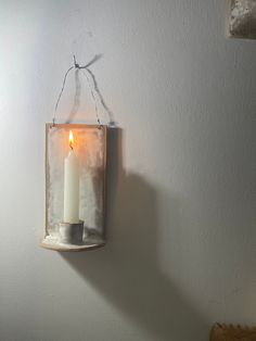 a candle hanging from a wall with a light on it